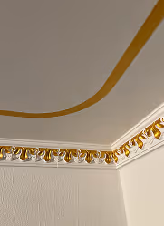Decke mit weißem Ornamentfries in Gold und goldfarbenem Band auf hellgrauer Oberfläche.