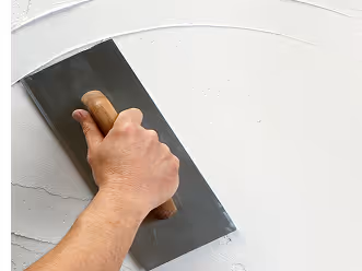 Hand glättet eine weiße Wand mit einer Glättkelle.